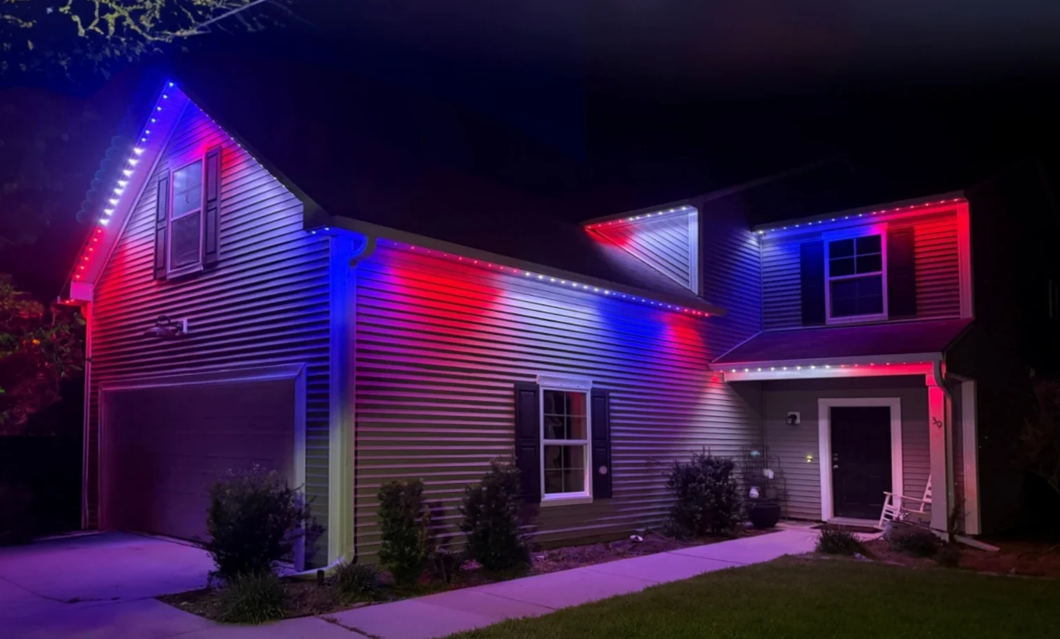 A home illuminated in red and blue with permanent roofline lights