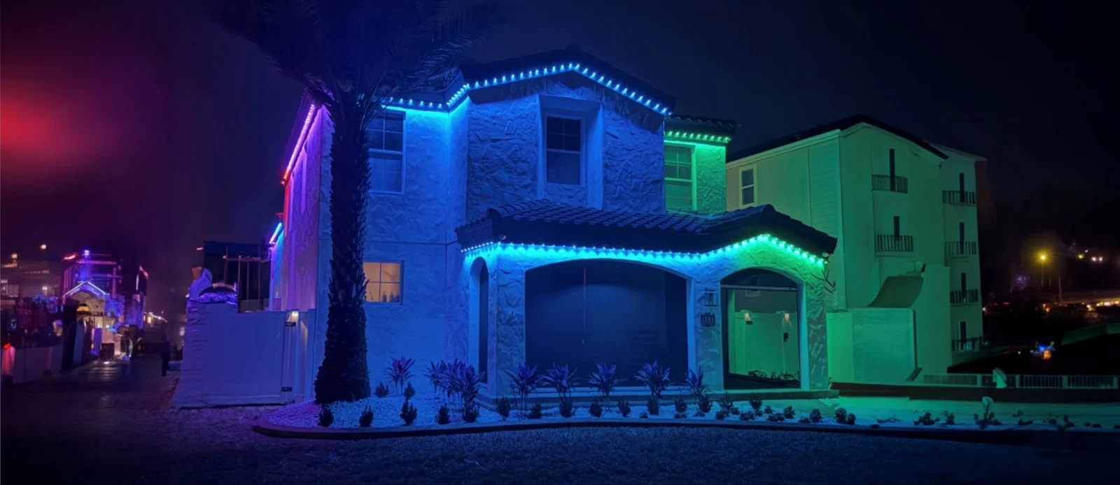 Blue and green permanent lights following the roofline of a two-story home