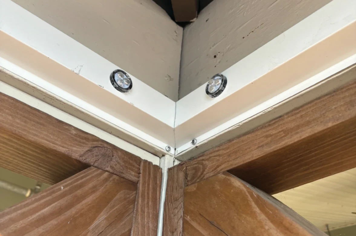 Small lighting pucks set into a white track beneath the eaves